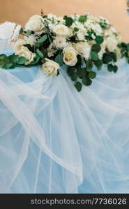 The presidium of the newlyweds in the banquet hall of the restaurant is decorated with candles and green plants, wisteria hangs from the ceiling