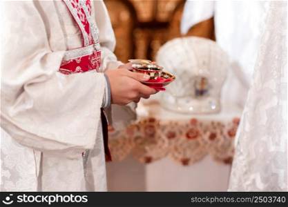 The priest blesses and hold cup the blood of God, wine. Priest celebrate a mass at the church. traditional wedding ceremony. Sacred cup for the wedding ceremony. High quality photo.. The priest blesses and hold cup the blood of God, wine. Priest celebrate a mass at the church. traditional wedding ceremony. Sacred cup for the wedding ceremony. High quality photo