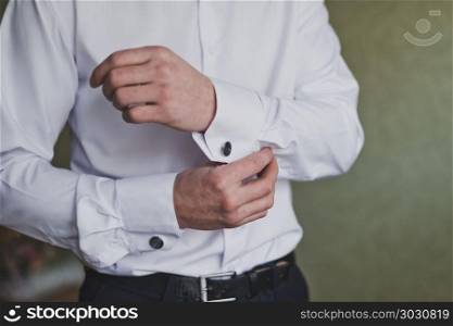The process of buttoning the sleeves of a white shirt by a man.. Man buttons cuff link on the sleeve of his shirt 1182.. Man buttons cuff link on the sleeve of his shirt 1182.