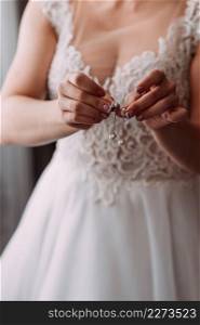 The process of equipping the bride before the wedding.. The bride in an openwork dress holds a necklace in her hands 3796.