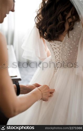 The process of equipping the bride on the wedding morning.. A friend ties a wedding dress on the bride 3982.