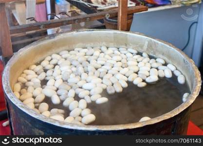 The process of extracting raw silk fiber from cocoons in a pan with water in the production of Istanbul, Turkey.. Boiling silkworm cocoon in a pan with water. A process of making silk cloth in Istanbul