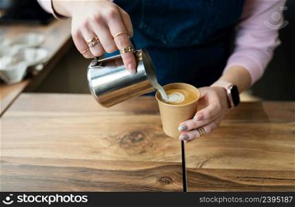 The process of making a barista cappuccino with a beautiful pattern on the foam in an eco-craft glass. Coffee to go concept. The process of making a barista cappuccino with a beautiful pattern on the foam in an eco-craft glass. Coffee to go concept.