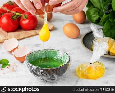 The process of making poached or benedict eggs. The cook pours an egg into a plate. Ingredients for making breakfast on the table. close-up, shallow depth of field. The idea of cooking.