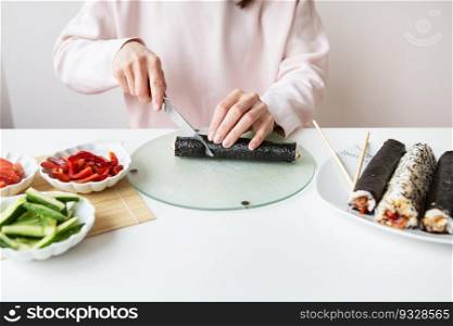 The process of making sushi, the girl makes sushi with different flavors - fresh salmon, caviar, avocado, cucumber, ginger, rice. Cut the roll into pieces. The process of making sushi, the girl makes sushi with different flavors - fresh salmon, caviar, avocado, cucumber, ginger, rice. Cut the roll into pieces.
