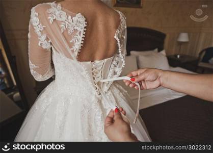 The process of setting the wedding bridesmaid dresses.. Girl helps lace up bridesmaid dress 541.