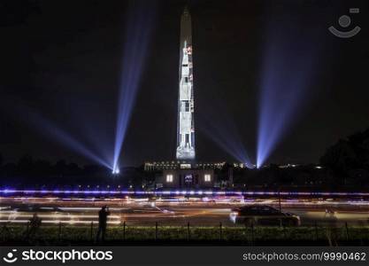 The projection of the Saturn V Apollo 11 rocket on the Washington Monument in Washington DC during the Summer of 2019 as police cars drive by.