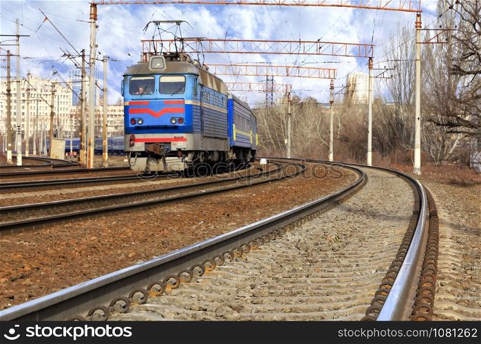 The prospect of many multi-lane railways for electric trains with overhead power lines in the early spring morning, high-rise buildings in the background.. Perspective and turn of a multichannel railway for electric trains