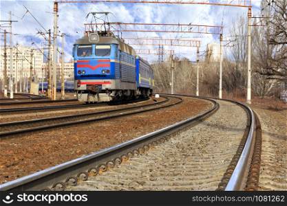 The prospect of many multi-lane railways for electric trains with overhead power lines in the early spring morning, high-rise buildings in the background.. Perspective and turn of a multichannel railway for electric trains