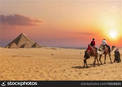 The Pyramid complex of Giza and arabs on camels, Egypt.. The Pyramid complex of Giza and arabs on camels, Egypt