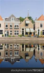 The quaint village of Spaarndam, the Netherlands, with it&rsquo;s old, picutresque houses reflected in the water on a warm summer morning, basiking in the light