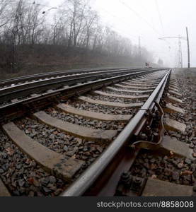 The railway track in a misty morning. A lot of rails and s≤epers go∫o the misty horizon. Fisheye photo with increased distortion