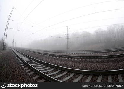 The railway track in a misty morning. A lot of rails and sleepers go into the misty horizon. Fisheye photo with increased distortion