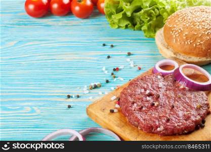 The raw ingredients for the homemade burger on blue wooden table. copy space for text.. The ingredients for the burger