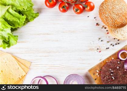 The raw ingredients for the homemade burger on white wooden table. Top view, flat lay with copy space for text. The ingredients for the burger