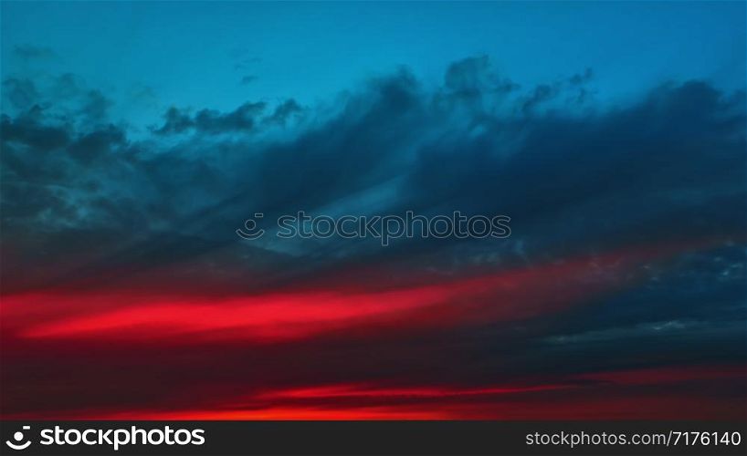 The red glow before dawn on a dark dramatic cloudy sky - an amazing colorful contrasting heavenly background with space for copy.