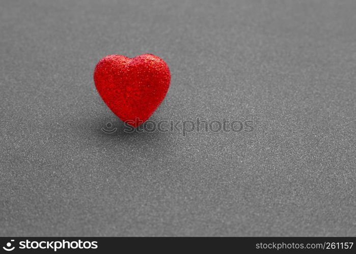 The red heart shape on dark grey glitter background in love concept for valentines day. Copy space