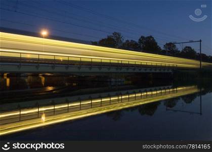 The reflection of an intercity train on a bridge at night