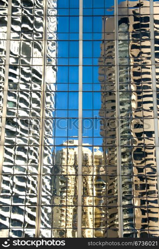 The reflections in the glass facade of an adjacent skyscraper of a nearby office tower