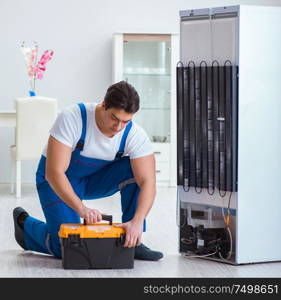 The repairman contractor repairing fridge in diy concept. Repairman contractor repairing fridge in DIY concept