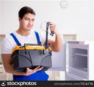 The repairman contractor repairing fridge in diy concept. Repairman contractor repairing fridge in DIY concept