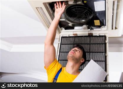 The repairman repairing ceiling air conditioning unit. Repairman repairing ceiling air conditioning unit