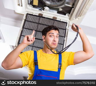 The repairman repairing ceiling air conditioning unit. Repairman repairing ceiling air conditioning unit