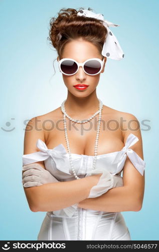 The retro photo of a cute pin-up girl in a vintage underwear holding her hands in a defensive position.