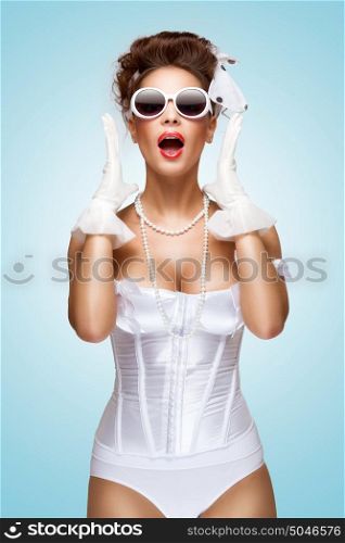 The retro photo of a shocked and surprised bride with stylish makeup in a vintage corset showing strong emotions.