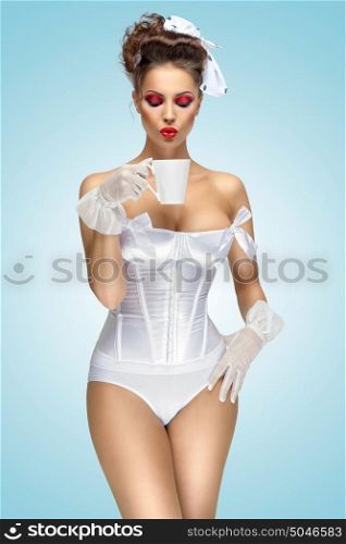 The retro photo of a vintage pin-up girl drinking a morning cup of tea, wearing a corset and stylish makeup.