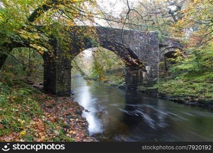 The River Dart and Holne Bridge. Dartmoor National Park, Devon, England, United Kingdom. Granite Bridge, autumn, fall, long exposure.