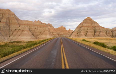 The road leads through rock formations in the South Dakota Badlands