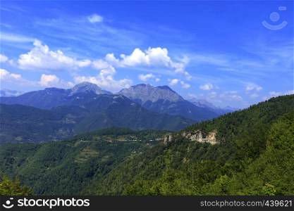 The road passes through a mountain tunnel and is hidden in the panoramic landscape of the rocky ridges of Montenegro overgrown with dense forest.. Mountain panoramic landscape of the rocky ridges of Montenegro overgrown with dense forest