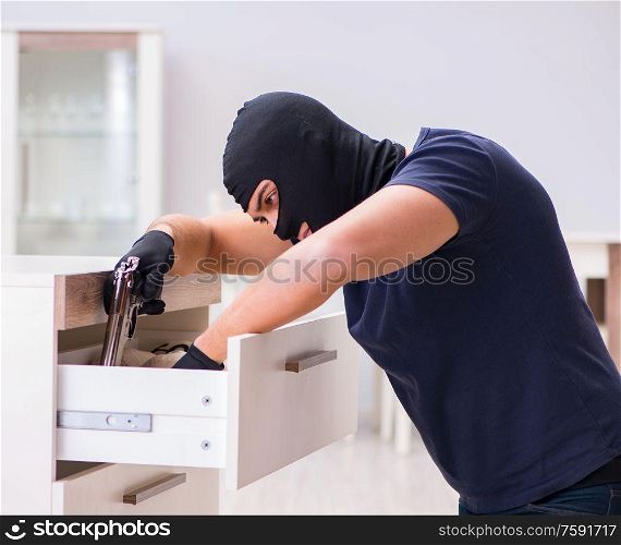 The robber wearing balaclava stealing valuable things. Robber wearing balaclava stealing valuable things