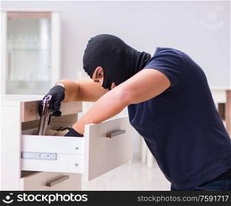 The robber wearing balaclava stealing valuable things. Robber wearing balaclava stealing valuable things