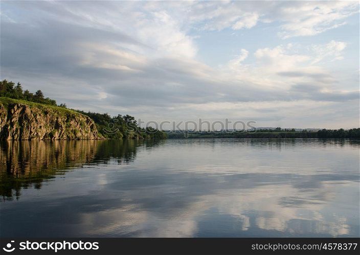 the rock river in the orange sunset light on the background of blue sky, river bed