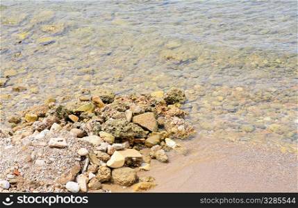 The rocky seashore with coming wave of green water..