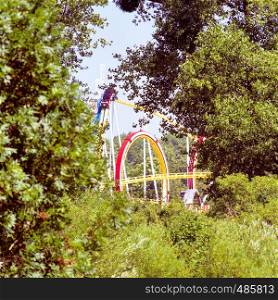 The roller coaster on the fairground of the shooting festival photographed from a great distance, with framed green bushes, shrubs and trees, Hannpver
