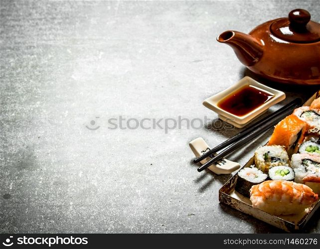 The rolls and sushi, herbal tea and soy sauce. On the stone table.. rolls , sushi and herbal tea