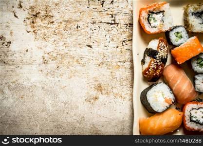 The rolls and sushi, seafood on the plate. On rustic background.. The rolls and sushi, seafood on the plate.