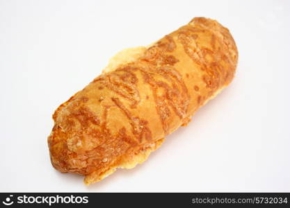 The ruddy long loaf of bread is strewed by cheese isolated on a white background