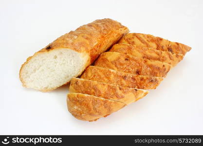 The ruddy long loaf of bread is strewed by cheese isolated on a white background