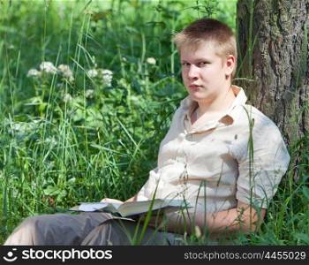 The school student reads the book in park on a grass