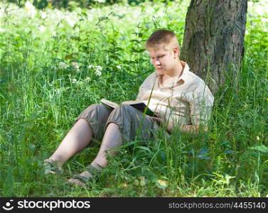 The school student reads the book in park on a grass