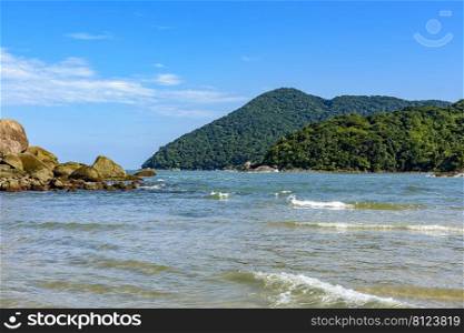 The sea with calm and transparent waters between the rocks, mountains and tropical forests of Bertioga on the coast of Sao Paulo, Brazil. The sea with calm and transparent waters between the rocks, mountains and rainforest