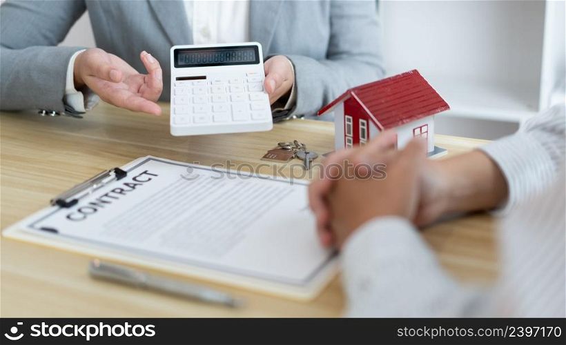 The selling agent informing his client about the expense by showing it on the calculator.