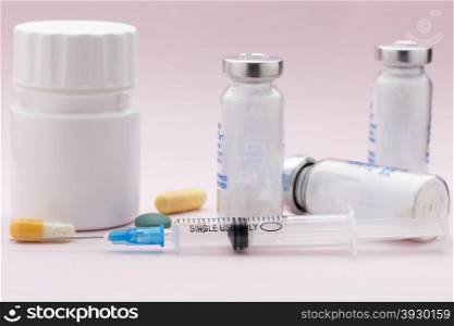 The set of colorful medicine pills and injection syringe. The set of colorful medicine pills and injection syringe on pink background