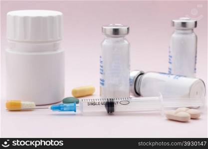 The set of medicine pill bottle and injection syringe. The set of medicine pill bottle and injection syringe on pink background