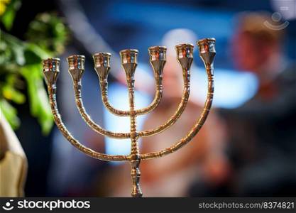 The seven-armed Menorah symbolizes the idea that the State of Israel may be a light-bringer and example to all nations.. Menorah in room with 7 arms Hanukkah symbol, selective focus
