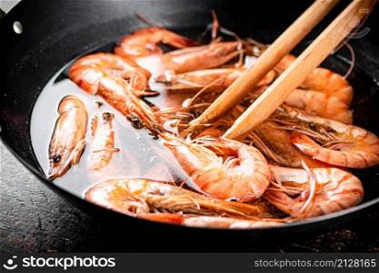 The shrimp are boiled in a pot of water. Against a dark background. High quality photo. The shrimp are boiled in a pot of water.